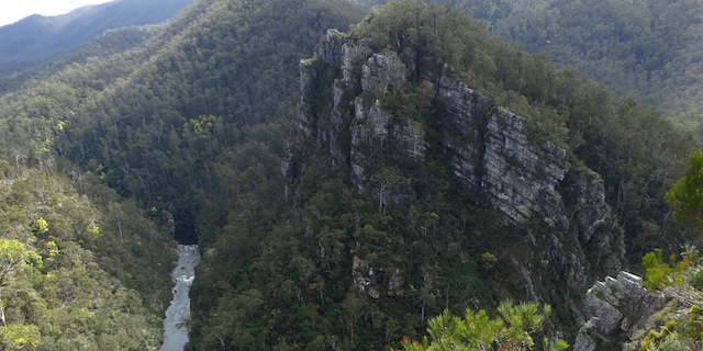 Layered white cliffs above river flowing through gorge
