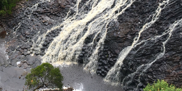 Photograph of water flowing across a sloping surface of basalt columns.